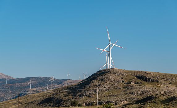 clean electricity producing wind turbine or windmill built on a windy mountain ridge