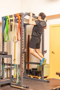 Sportsman doing pull ups with bar in gym. Concept of exercises with equipment in gym.