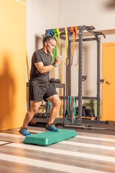 Sportsman doing step up jumps in health club. Concept of exercises with equipment in health club.