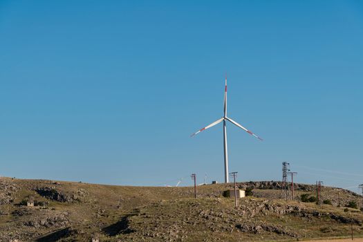 clean electricity producing wind turbine or windmill built on a windy mountain ridge