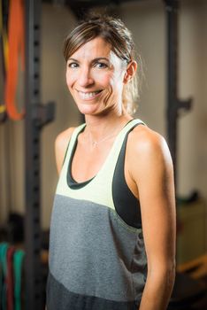 Portrait of cheerful athlete woman in gym looking at camera. Concept of people in gym.