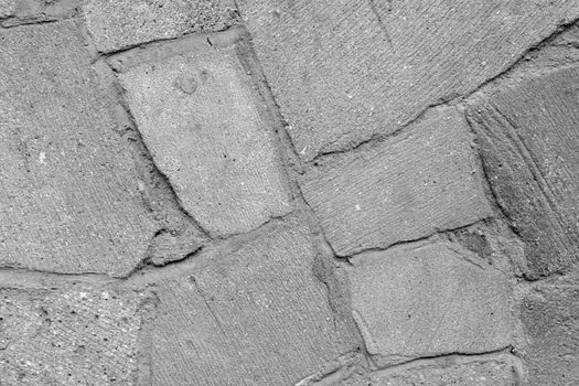 The gray texture of the stone wall of the building, the background of concrete