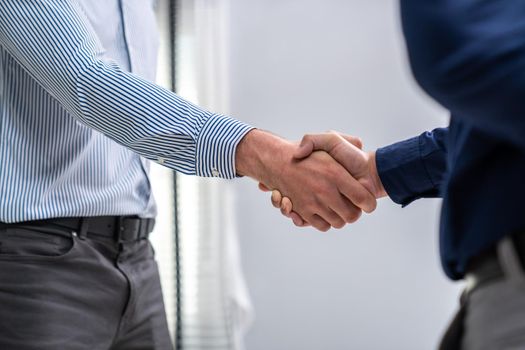 Two competent businessmen shake hands after successfully concluding a trading arrangement or business meeting.