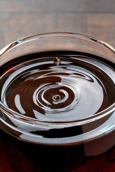 Drops of wine and waves forming in a glass full of red wine standing on a wooden table