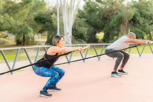 Fitness people exercising with an elastic gym stick in the park. Multi-ethnic people exercising outside.