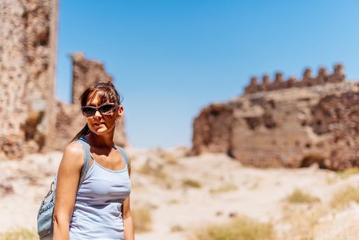 Young woman in sunglasses and summer clothes visiting a restored medieval castle. Almonacid Castle in Spain