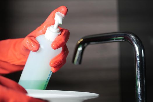 hand in gloves cleaning a white color plate .