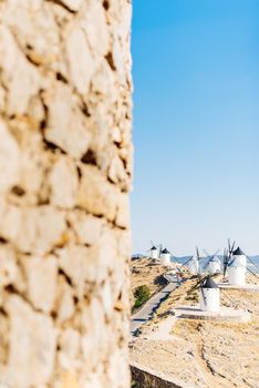 Vertical photo with selective focus and copy space of a group of historic windmills on a hillside with fields in the background the image in Spain