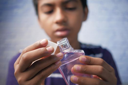 teenage boy hold a mouthwash liquid container ,