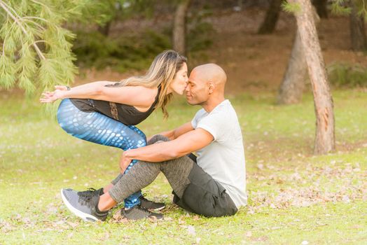 Fitness couple doing excersise while she kissing him in the nose. Couple doing exercise outdoors together.