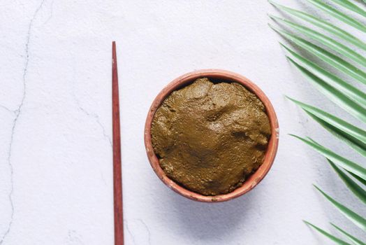 The wooden bowl with rehydrated henna on table .