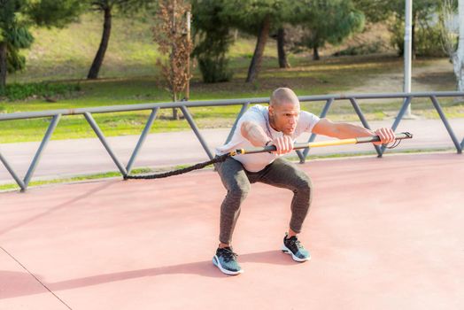 Sportsman exercising with an elastic gym stick in the park. Latino man exercising outside.