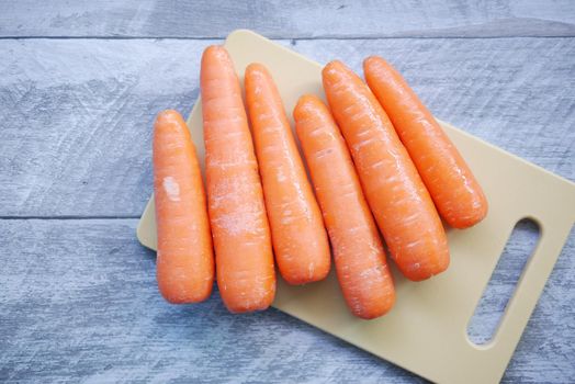 fresh carrots on chopping board on table .