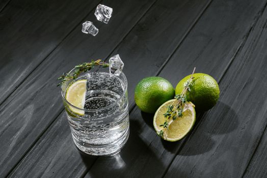 hard seltzer with lime on a dark wooden background, ice cubes fall into a glass with an alcoholic drink hard seltzer.