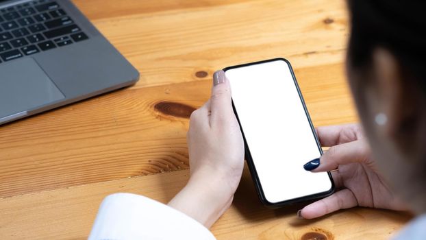 hand woman using a telephone, empty screen smart phone and computer on wooden table top view