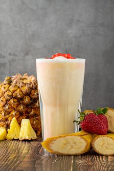 Banana, strawberry and pineapple smoothie on wooden table and bubble tea or boba tea balls on it