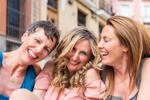 Three laughing mature friends together looking at the camera. Middle aged friends sharing time together and having fun.