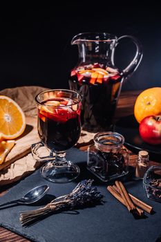 Still life - mulled wine, hot red wine with spices in glass among fruits. Scented cozy Christmas celebration, fragrant punch concept. High quality