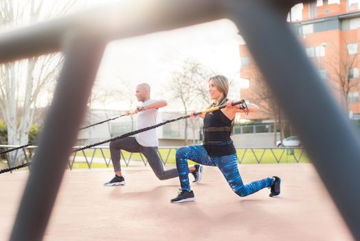 Athletic people exercising with an elastic gym stick in the park. Multi-ethnic people exercising outside.