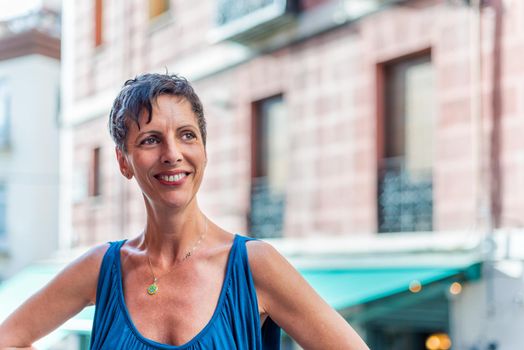 Portrait of a cheerful mature woman on the street. Middle aged woman in the city looking away.