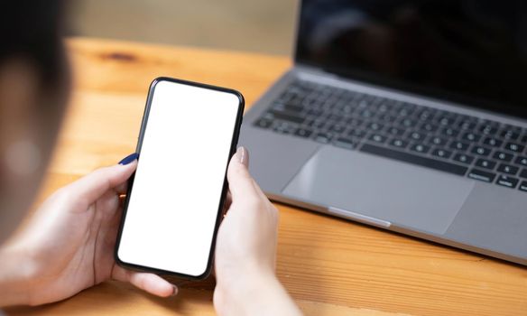 hand woman using a telephone, empty screen smart phone and computer on wooden table top view