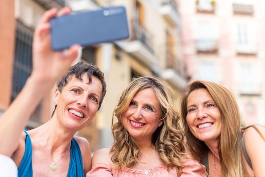 Three mature female friends taking a selfie in the city. Middle aged friends sharing time together and having fun.