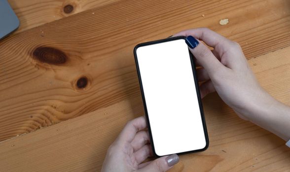 hand woman using a telephone, empty screen smart phone and computer on wooden table top view