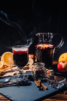 Stunning view of hot mulled wine with honey, fruits and spices. Fragrant atmosphere of Christmas winter holiday. Glass with cinnamon and orange on table.High quality