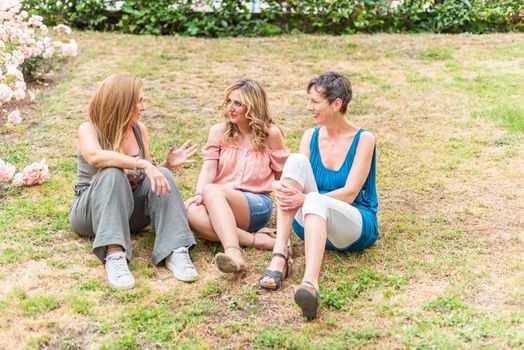 Front view of three mature women sitting in the park chatting. Beautiful mature women having a good time together in the park.