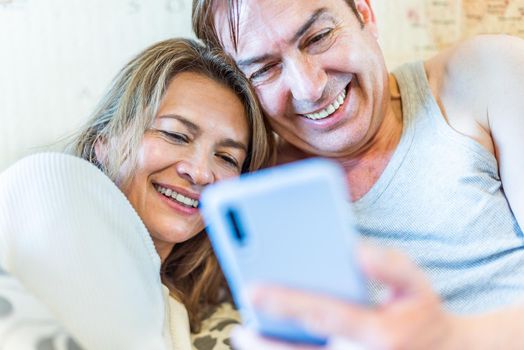 Happy middle-aged couple looking at mobile smiling. High quality photo