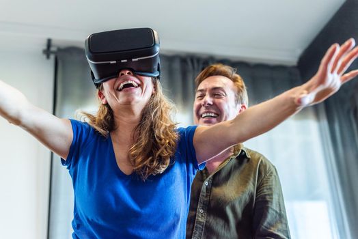 Mature married couple at home playing with virtual reality glasses. High quality photo