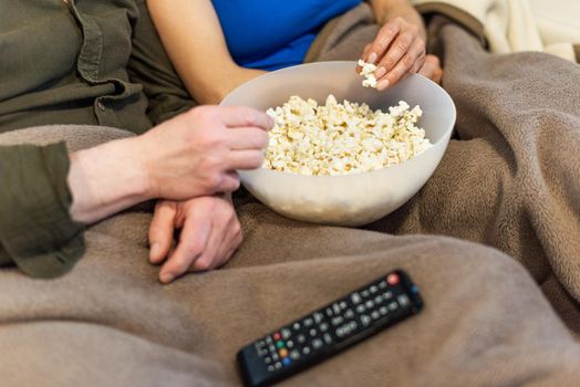 Popcorn bowl detail. Unrecognizable man and woman. High quality photo