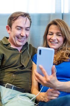 Mature married couple listening to music with headphones on. High quality photo