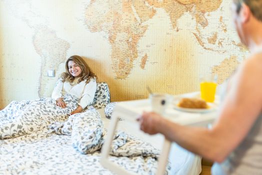 Mature man in love bringing his wife breakfast in bed on a tray. High quality photo