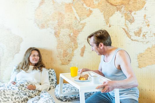 Mature man in love bringing his wife breakfast in bed on a tray. High quality photo