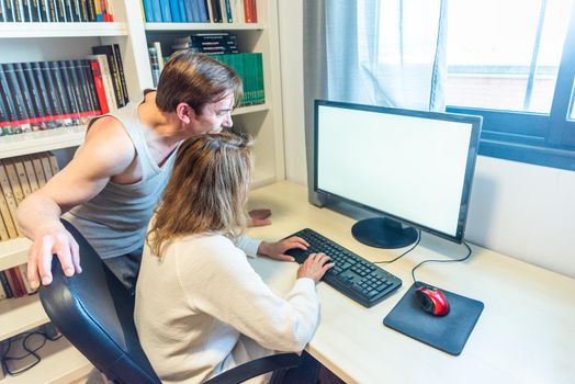 Mature aged couple with their back turned working in front of the computer. High quality photo