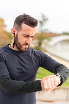 Young runner man with headphones training and checking stopwatch. High quality photo