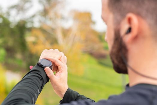 Young runner man with headphones training and checking stopwatch. Detail. Unrecognizable.