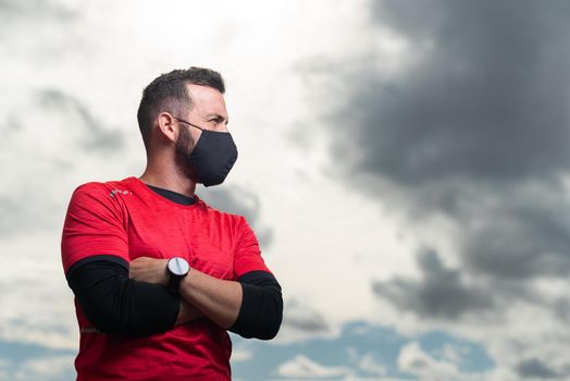 Sportsman with crossed arms wearing a face mask looking to the side. High quality photo
