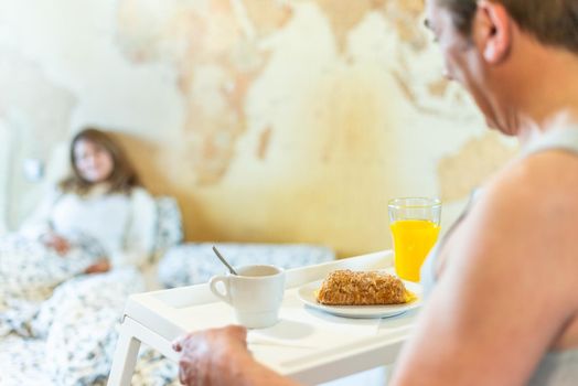 Mature man in love bringing his wife breakfast in bed on a tray. High quality photo