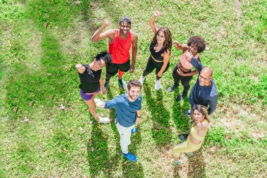 Group of runners waving at camera with raised fists. Top view. Horizontal framing.