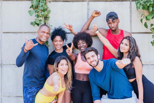 Portrait of a group of runners smiling at camera with raised fists. Horizontal framing.