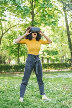 Afro woman wearing a virtual reality glasses in a garden. Selective focus.