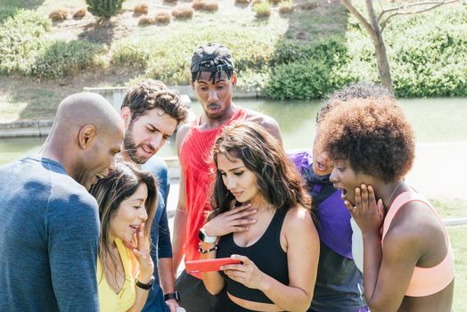 Group of runners very surprised when looking at something on a mobile. Horizontal framing.