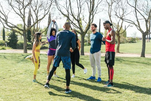 Group of friendly runners talking in a park before training. Selective focus.