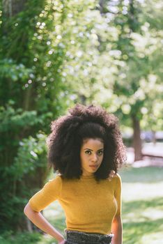 Portrait of nice afro girl in a garden. Mid shot. Selective focus.