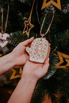 Woman decorating Christmas tree with gingerbread mitten cookie. Holiday concept. High quality photo