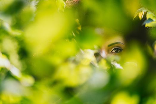 Nice portrait of beautiful afro woman through the leaves. SELECTIVE FOCUS.