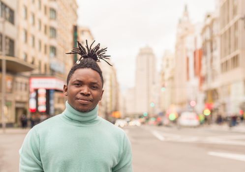 Black guy in the middle of the city looking at camera seriously. Selective focus.