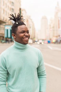 Young black man in the middle of the city, smiling. Selective focus.